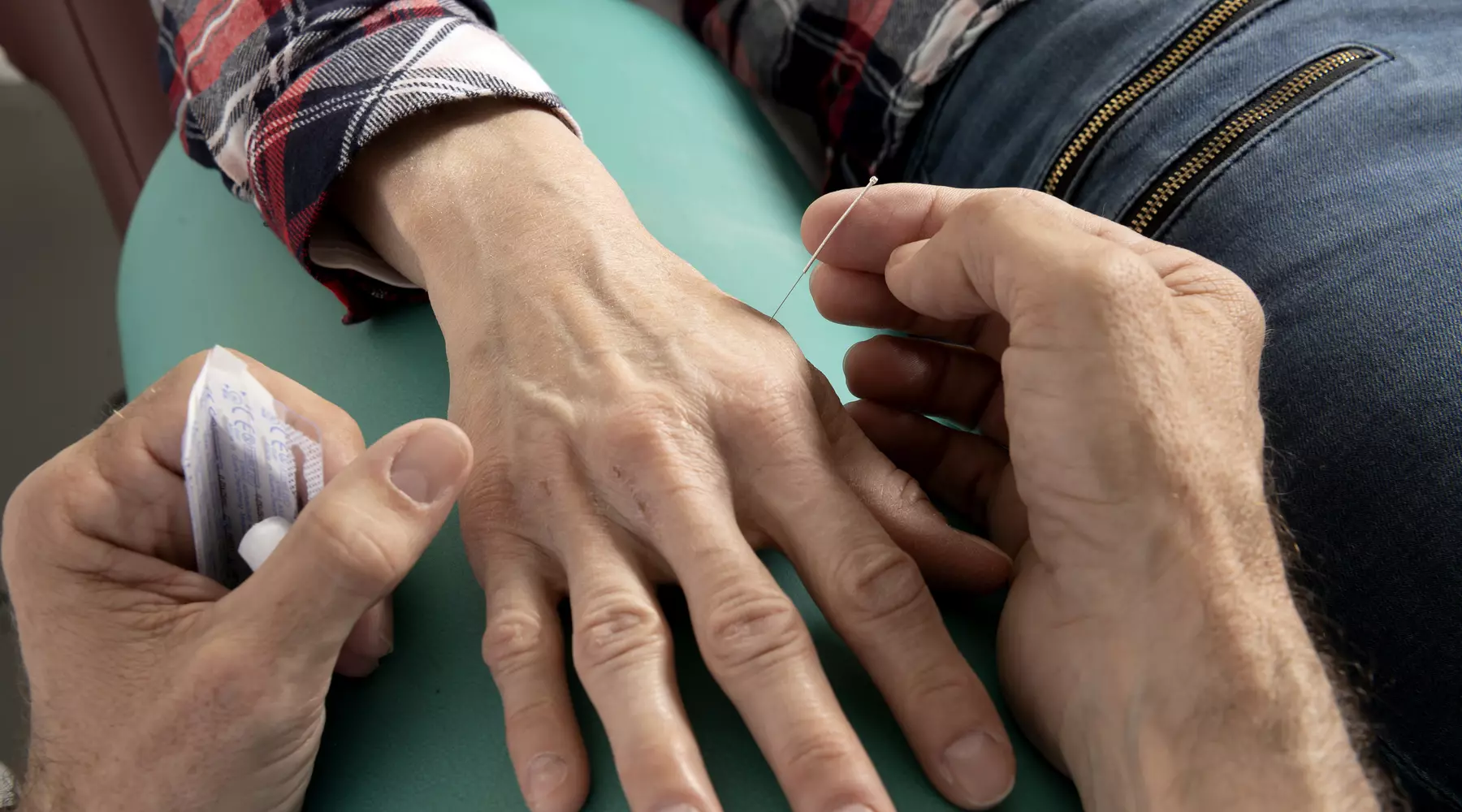 Gros plan sur les mains du médecin en train d'appliquer des aiguilles sur les mains d'une patiente