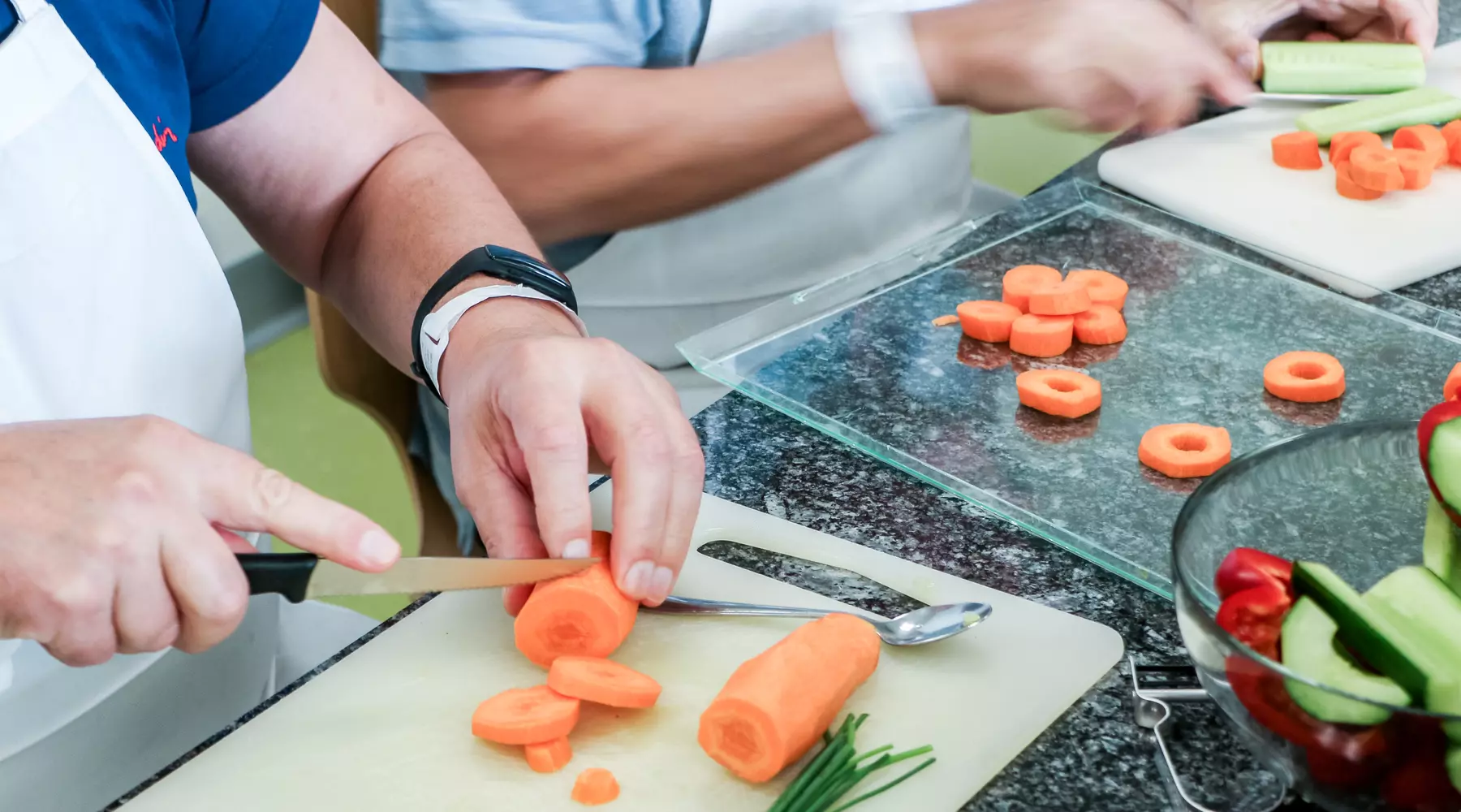 Gros plan sur les mains de patients en train de découper des carottes dans le cadre d'une formation sur l'alimentation