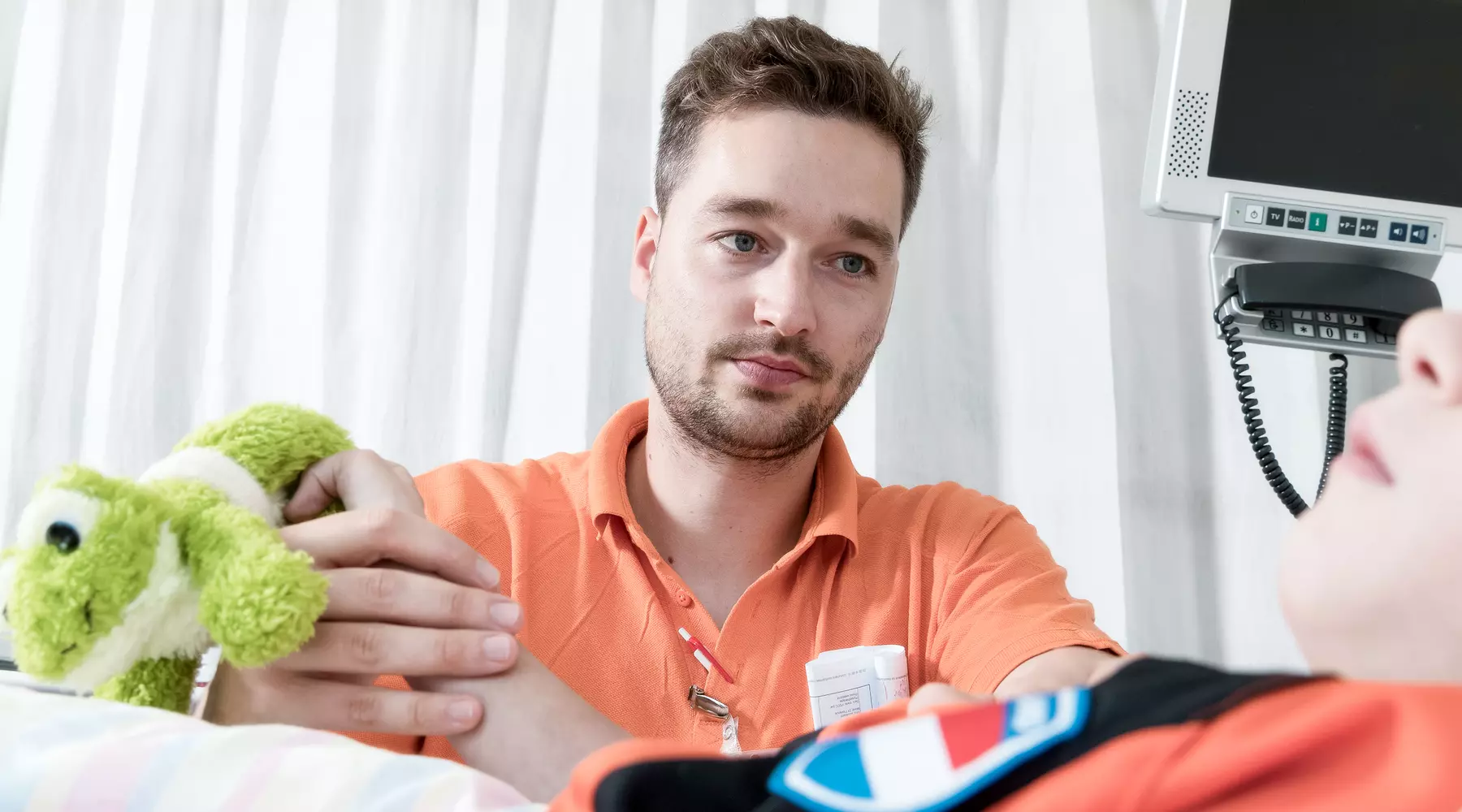 Photo d'un physiothérapeute manipulant le bras d'un enfant. Ce dernier tient une peluche dans la main.