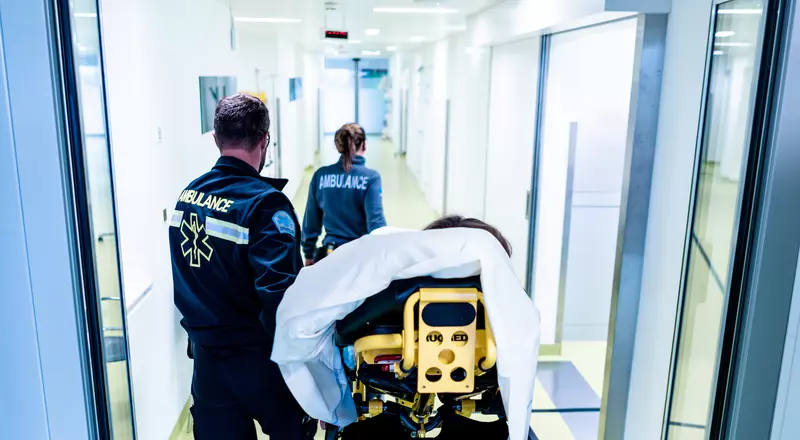 Deux urgentistes poussent le lit d'un patient dans un couloir