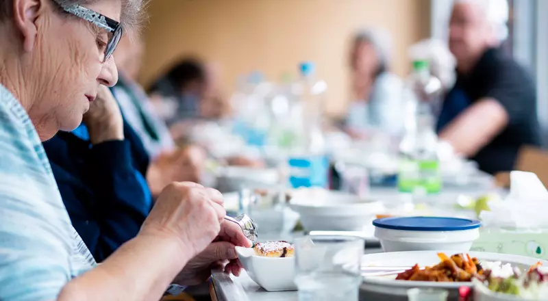 Ältere Patienten essen gemeinsam an einem Tisch