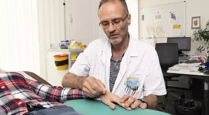 Dr Köhler en train de pratiquer l'acupuncture sur la main d'un patient