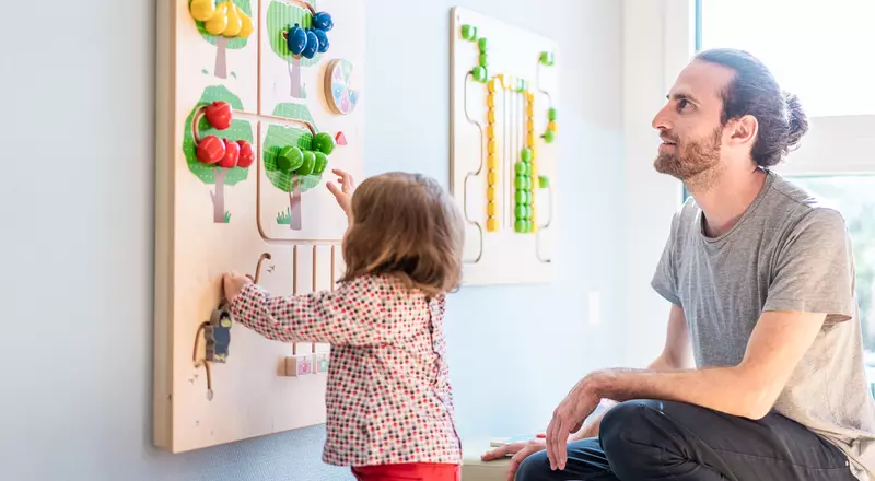 Une petite fille joue sous le regard attendri de son père