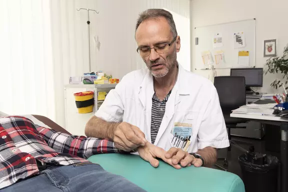 Dr Köhler en train de pratiquer l'acupuncture sur la main d'un patient