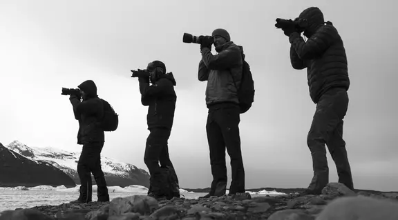 Photo en noir et blanc des 4 photographes, tous ont l'oeil rivé à leur caméra.